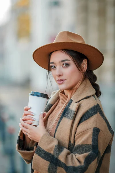 Yakın plan, şapkalı, kahve içen güzel bir kadın Avrupa 'da yürüyor.