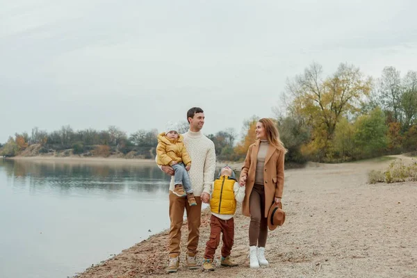 Güzel, mutlu bir aile ve gölün kenarında yürüyen çocuklar.