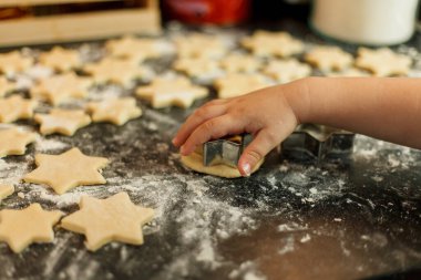 Küçük kız yıldız şeklinde kurabiye pişirir. Noel kurabiyeleri.