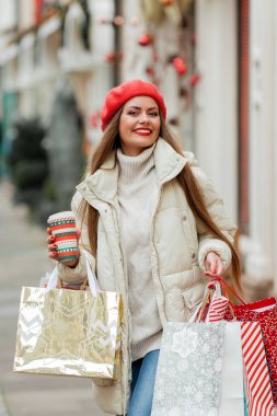 Güzel genç bayan Noel alışverişi yapıyor. Bir Avrupa şehrinin caddesinde kırmızı bereli genç bir kadının portresi..