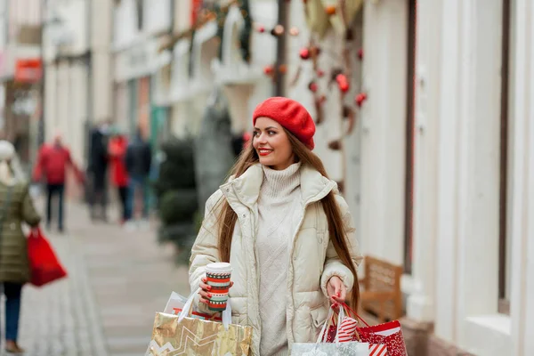 漂亮的年轻女子正在采购圣诞礼物 欧洲城市街道上一个戴着红色贝雷帽的年轻女子的画像 — 图库照片