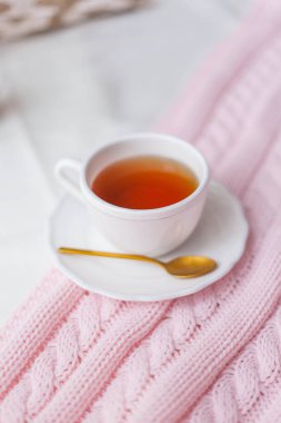 Bir kupa sıcak çay, yatağın üzerine pembe bir ekose örgü. Yatakta kahvaltı. Samimi. Bahar.