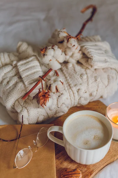 Decoração aconchegante casa. Uma caneca de cappuccino, bolachas, uma vela na cama. Manhã de inverno. — Fotografia de Stock