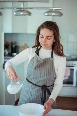 Genç ve güzel bir kadın kek pişiriyor. Tatlılar.