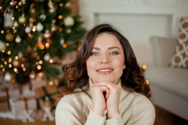 Noel ağacının yanında güzel genç bir kadın. Kadın hediyeleri açıyor. Tatillerde. Kış.