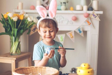 Paskalya. Küçük bir çocuk Paskalya yumurtalarını boyuyor. Paskalya dekoru. Tatiller.