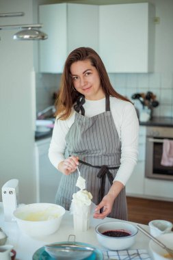 Genç ve güzel bir kadın kek pişiriyor. Tatlılar.