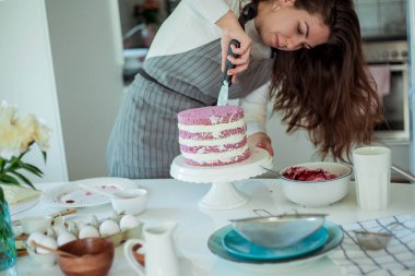 Genç ve güzel bir kadın kek pişiriyor. Tatlılar.