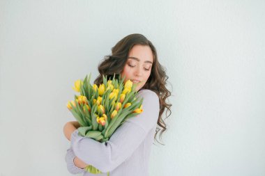 Kıvırcık saçlı güzel genç bir kadın bir buket lale tutuyor. Kadınlar Günü.