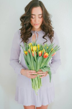 Kıvırcık saçlı güzel genç bir kadın bir buket lale tutuyor. Kadınlar Günü.