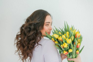Kıvırcık saçlı güzel genç bir kadın bir buket lale tutuyor. Kadınlar Günü.