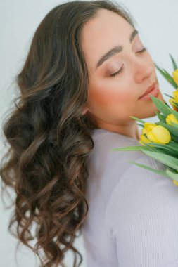 Kıvırcık saçlı güzel genç bir kadın bir buket lale tutuyor. Kadınlar Günü.
