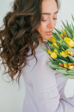 Kıvırcık saçlı güzel genç bir kadın bir buket lale tutuyor. Kadınlar Günü.