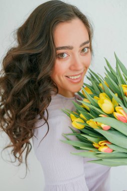 Kıvırcık saçlı güzel genç bir kadın bir buket lale tutuyor. Kadınlar Günü.