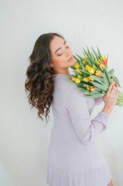 Kıvırcık saçlı güzel genç bir kadın bir buket lale tutuyor. Kadınlar Günü.