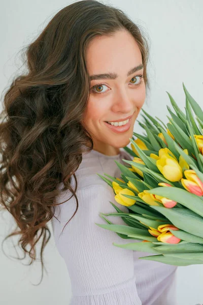 Kıvırcık saçlı güzel genç bir kadın bir buket lale tutuyor. Kadınlar Günü.