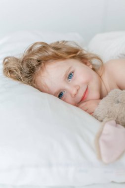 Uyuyan ve peluş tavşanına sarılan küçük bir kızın yakın çekimi. Rahatlama. İyi uykular. Samimi.