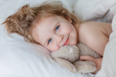 Uyuyan ve peluş tavşanına sarılan küçük bir kızın yakın çekimi. Rahatlama. İyi uykular. Samimi.