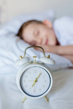 Alarmlı saati olan öğrenci yatakta uyuyor. Günaydın..