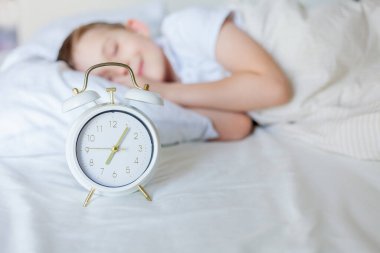 Alarmlı saati olan öğrenci yatakta uyuyor. Günaydın..