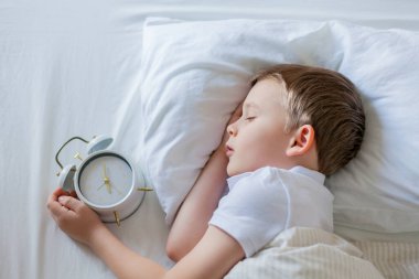 Alarmlı saati olan öğrenci yatakta uyuyor. Günaydın..