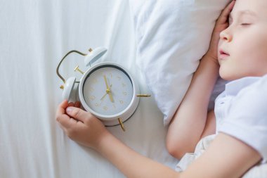 Alarmlı saati olan öğrenci yatakta uyuyor. Günaydın..