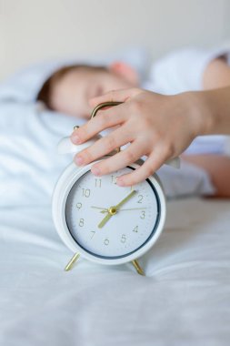 Alarmlı saati olan öğrenci yatakta uyuyor. Günaydın..