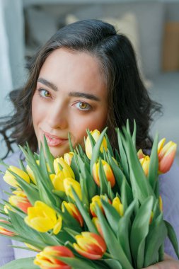 Kıvırcık saçlı güzel genç bir kadın bir buket lale tutuyor. Kadınlar Günü.