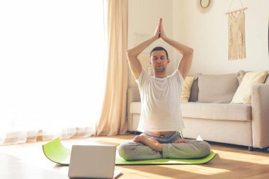 Yoga yapan genç bir adam. Evde çevrimiçi dersler.