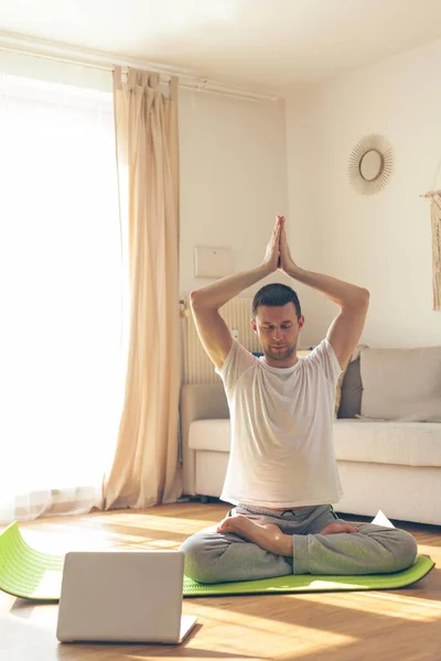 Yoga yapan genç bir adam. Evde çevrimiçi dersler.