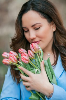 Mavi takım elbiseli, bir buket lale taşıyan güzel bir genç kadının portresi..