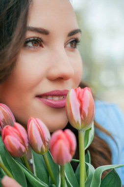 Mavi takım elbiseli, bir buket lale taşıyan güzel bir genç kadının portresi..