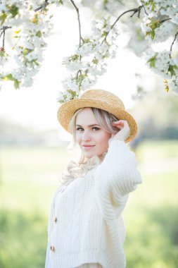 Güzel genç bir kadın çiçek açan bir bahçede piknikte dinleniyor. Beyaz çiçekler. Bahar.