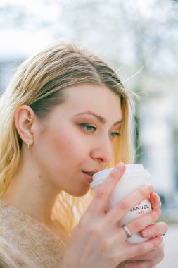 Güzel genç bir kadın Avrupa 'da bir şehrin sokaklarında kahve içer. Mutluluk.