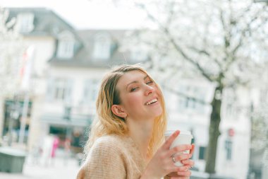 Güzel genç bir kadın Avrupa 'da bir şehrin sokaklarında kahve içer. Mutluluk.