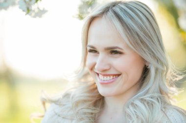 Güzel genç bir kadın çiçek açan bir bahçede piknikte dinleniyor. Beyaz çiçekler. Bahar.