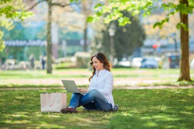 Genç mutlu kadın doğada bir dizüstü bilgisayarda çalışıyor. Karantinaya alın. Serbest çalışan biri. Şehir.