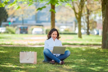Genç mutlu kadın doğada bir dizüstü bilgisayarda çalışıyor. Karantinaya alın. Serbest çalışan biri. Şehir.
