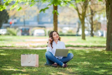 Genç mutlu kadın doğada bir dizüstü bilgisayarda çalışıyor. Karantinaya alın. Serbest çalışan biri. Şehir.