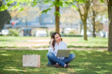 Genç mutlu kadın doğada bir dizüstü bilgisayarda çalışıyor. Karantinaya alın. Serbest çalışan biri. Şehir.