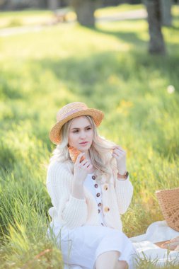 Güzel genç bir kadın çiçek açan bir bahçede piknikte dinleniyor. Beyaz çiçekler. Bahar.