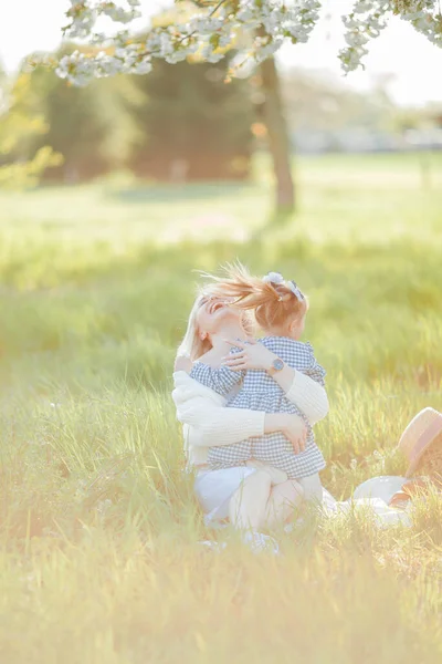一位漂亮的年轻母亲和她的小女儿正在花园子里野餐 白色的花春天 — 图库照片