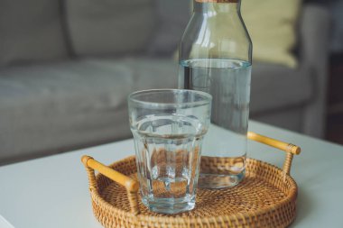 İç mekan. Bir bardak su, bir bardak, sehpanın üzerinde rattan hasır bir tepsi. Samimi.