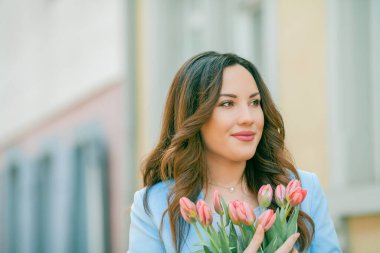 Mavi takım elbiseli, bir buket lale taşıyan güzel bir genç kadının portresi..