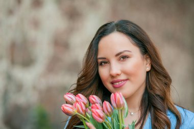 Mavi takım elbiseli, bir buket lale taşıyan güzel bir genç kadının portresi..