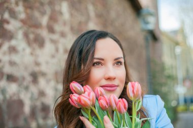 Mavi takım elbiseli, bir buket lale taşıyan güzel bir genç kadının portresi..