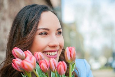 Mavi takım elbiseli, bir buket lale taşıyan güzel bir genç kadının portresi..