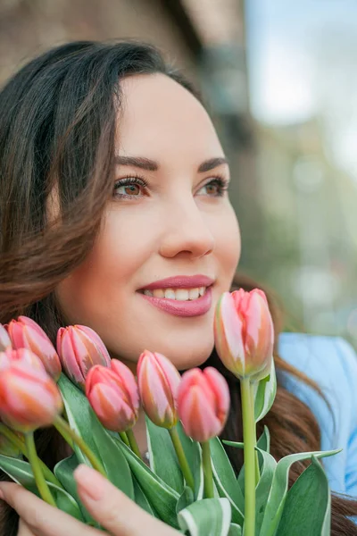 Mavi takım elbiseli, bir buket lale taşıyan güzel bir genç kadının portresi..