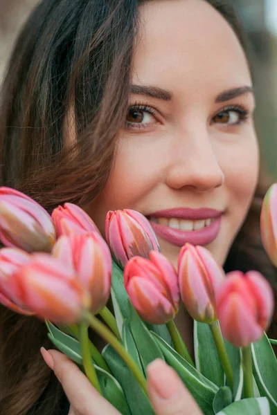 Mavi takım elbiseli, bir buket lale taşıyan güzel bir genç kadının portresi..