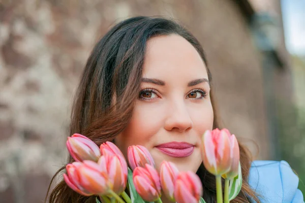 Mavi takım elbiseli, bir buket lale taşıyan güzel bir genç kadının portresi..